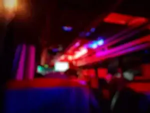 Blurry image of a bus interior at night, with vibrant red, pink, purple, and blue lights illuminating the ceiling and seats—like the colorful ambiance you'd see after booking a black car service in Newark, NJ.